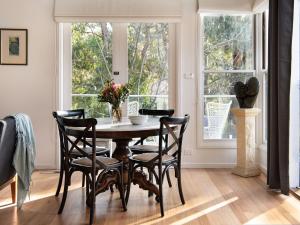 een eetkamer met een tafel en stoelen en een raam bij Lake Como Villa in Daylesford