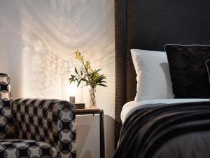 een slaapkamer met een bed en een stoel en een vaas met bloemen bij Lake Como Villa in Daylesford