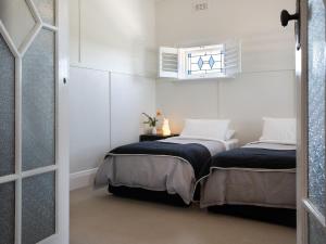 two beds in a room with white walls at Churchills in Daylesford