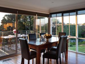 a dining room with a table and chairs and windows at Churchills in Daylesford