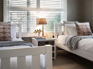 a bedroom with two white beds and a window at Green Gully House - a scenic country retreat in Glenlyon