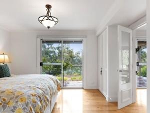 Dormitorio blanco con cama y ventana grande en Margies on Mt Franklin 8 minutes from Daylesford, en Hepburn Springs