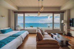 - une chambre avec une grande fenêtre, un lit et un canapé dans l'établissement ホテル 美らビーチ, à Motobu