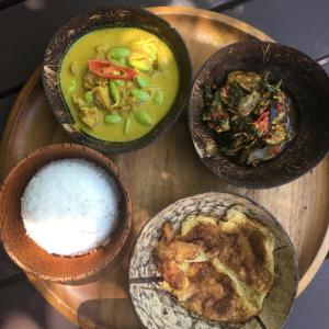 three bowls of food on a wooden table with rice at Jasmine & Tea House in Mae Nam