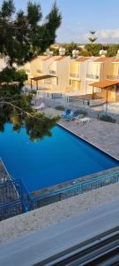 a swimming pool with blue water in front of buildings at Latchi Area Apartments in Lachi