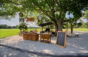 un parc avec des tables et un panneau sous un arbre dans l'établissement CondoHotel En Riviera Maya, Playa del Carmen, à Playa del Carmen