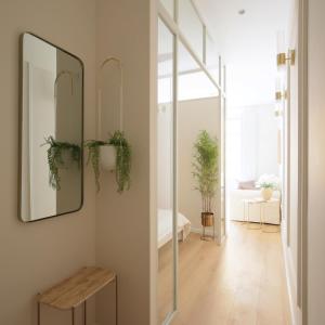 マドリードにあるSTAYLISH STUDIO APARTMENT IN MALASANAの鏡と植物が壁に掛けられた廊下