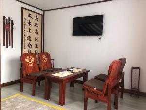 シギショアラにあるCasa Lily - Japanese Retreatの椅子2脚、テーブル、テレビが備わる客室です。