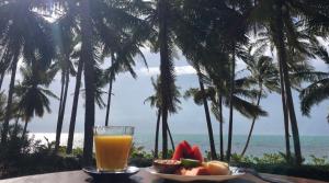 a glass of orange juice and fruit on a table with the beach at Jasmine & Tea House in Mae Nam