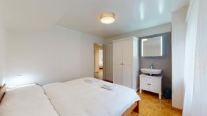 a bedroom with a white bed and a sink at Modern and charming apartment on the shores of Lake Lucerne in Gersau