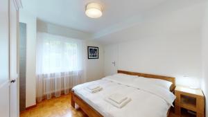 una camera da letto con un letto con lenzuola bianche e una finestra di Modern and charming apartment on the shores of Lake Lucerne a Gersau