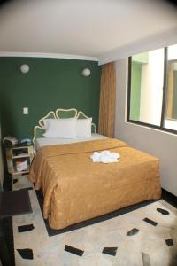 a bedroom with a large bed with a green wall at Hotel Business in Bogotá