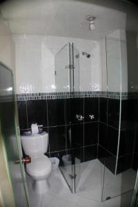 a bathroom with a toilet and a glass shower at Hotel Business in Bogotá