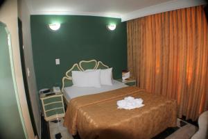 Habitación de hotel con cama y pared verde en Hotel Business, en Bogotá