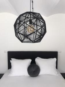 una luz colgante negra sobre una cama con almohadas blancas en Sotto La Vigna Charm Stay Adults only vacation Bed and breakfast room, en Montegrosso dʼAsti