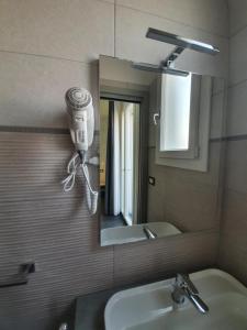 Un espejo de baño con un secador de pelo en la pared. en Evergreen B&B, en Porto Cesareo 17 fotos más