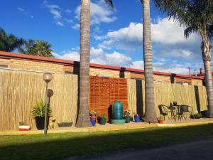 a fence with palm trees in front of a building at Sandbar Motel in Lakes Entrance