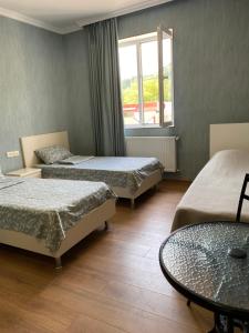 a room with three beds and a table and a window at Guesthouse Evergreen in Oni