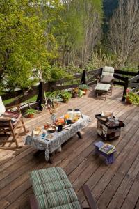 una terraza de madera con una mesa con comida. en Vasilikia Mountain Farm & Retreat en Pávliani