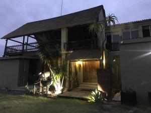 Casa con porche y balcón por la noche en Sunset Lodge & Safaris, en Guernsey Nature Reserve