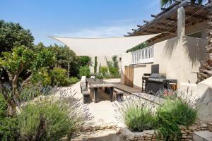 un patio con una mesa de madera y un banco de picnic en La Villa Les Petits Gardons, en Castillon-du-Gard