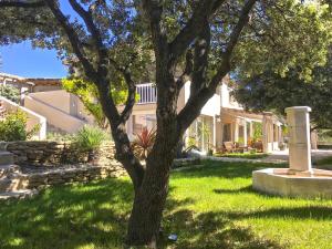 una casa con un árbol en el patio en La Villa Les Petits Gardons, en Castillon-du-Gard