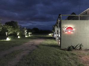 a dirt road at night with lights on a fence at Sunset Lodge & Safaris in Guernsey Nature Reserve