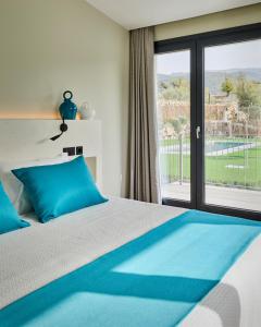 una camera da letto con un letto con cuscini blu e una finestra di Hotel Boutique Molino de Enmedio a Huéneja