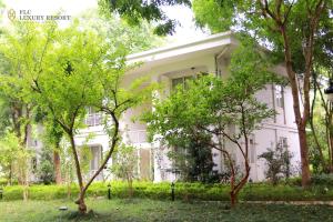 a white house with trees in front of it at FLC Luxury Resort Vinh Phuc in Hoằng Xá