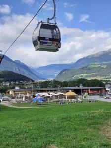 a gondola lift over a green field with mountains at Appartamento Riscone Nuvola di Plan in Brunico