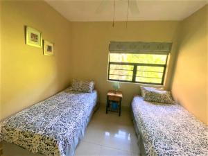 two beds in a room with a window at Lazy Lizard 51 in Umdloti