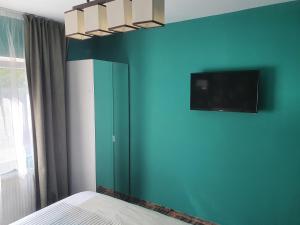 a bedroom with a blue wall with a tv on the wall at Meny Apartaments in Codlea