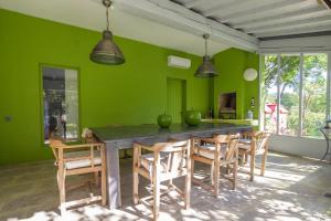uma sala de jantar com paredes verdes e uma mesa e cadeiras em La Grange Capelle em Villeneuve-lès-Avignon