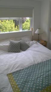 1 cama blanca con 2 almohadas y ventana en Chauffeur's, Snape, en Saxmundham