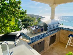 a outdoor kitchen with a grill and a view of the ocean at Sandcastle Villa & Beach House in The Valley