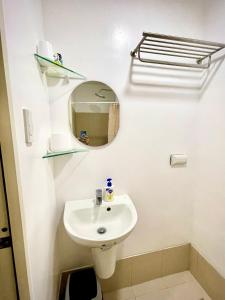 a white bathroom with a sink and a mirror at Cozy @ Cool in Tagaytay