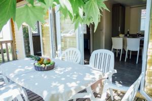 - une table avec des chaises blanches et une corbeille de fruits dans l'établissement Vignale Resort, à Ghisonaccia
