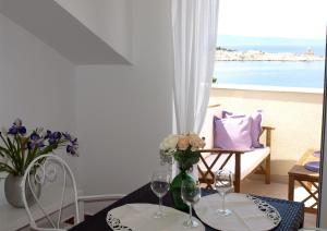 a table with wine glasses and a view of the ocean at Apartments Issa in Makarska