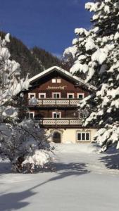 a large building in the snow with snow covered trees at Sonnenhof in Kals am Großglockner