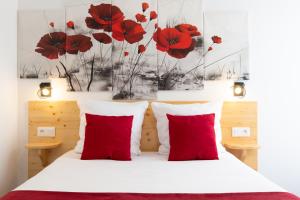 1 dormitorio con almohadas rojas y amapolas rojas en la pared en hotel le beauséjour, en Langogne