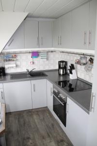a kitchen with white cabinets and a black counter top at Pumuckl in Husum