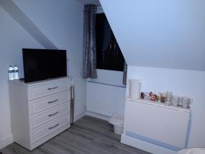 een slaapkamer met een witte dressoir en een televisie. bij Glenbeg Lodge B&B in Rathdrum