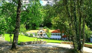 a large white house with trees in front of it at Pensão Continental Machado in Caldelas