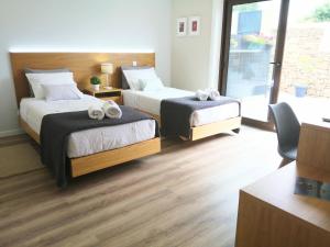 two beds in a room with wooden floors at Jardim das Oliveiras - Suítes com Vista in Ponte de Lima