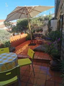 Un patio con una sombrilla y una mesa y sillas. en Casa Batalla, en Casar de Cáceres