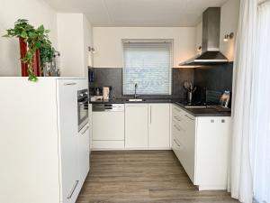 een keuken met witte kasten en een raam bij Hello Zeeland - Vakantiehuis Zwin 182 in Breskens