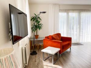 een woonkamer met een oranje bank en een tv bij Hello Zeeland - Vakantiehuis Zwin 182 in Breskens