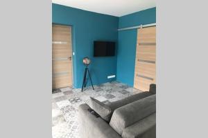 sala de estar con sofá y pared azul en Logement attenant à une villa T2 avec terrasse ., en Besse-sur-Issole