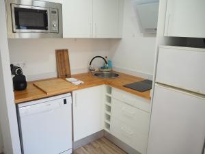 eine kleine Küche mit weißen Schränken und einem Waschbecken in der Unterkunft Apartament amb piscina i aparcament - Baixos amb jardinet in Calella de Palafrugell