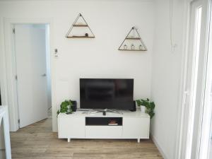 ein Wohnzimmer mit einem TV auf einem weißen Schrank in der Unterkunft Apartament amb piscina i aparcament - Baixos amb jardinet in Calella de Palafrugell